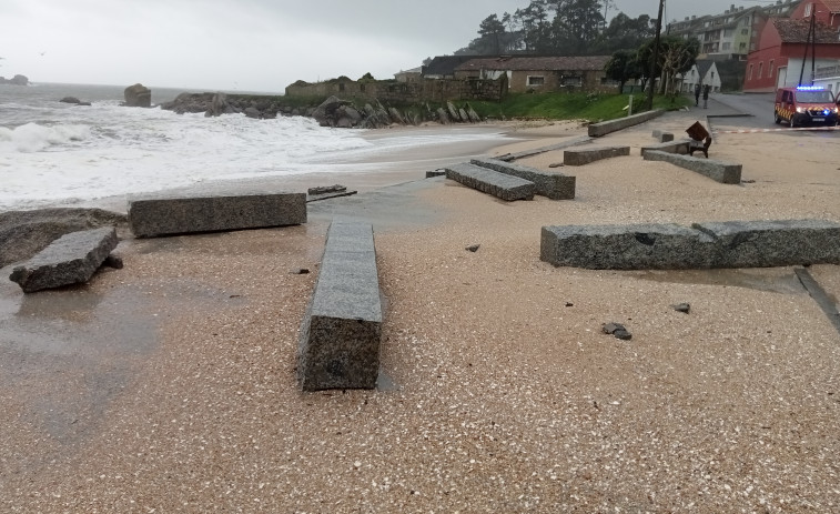 El fuerte oleaje derriba el petril que separa el paseo marítimo de la playa de Area Secada, en Ribeira